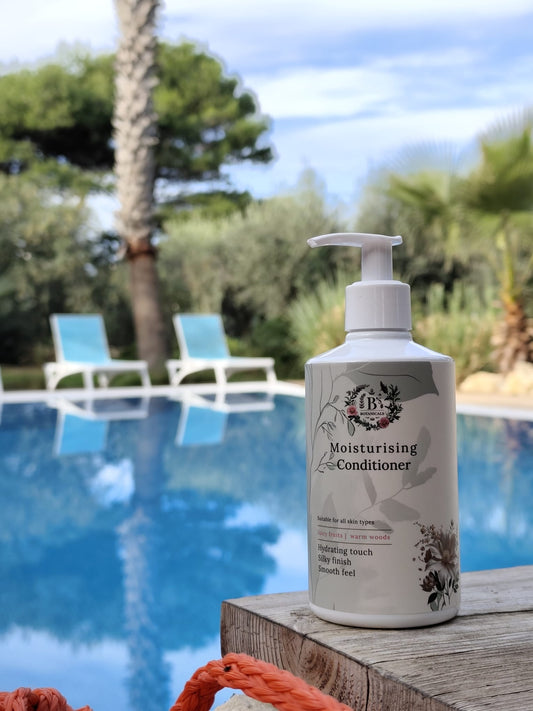 Moisturizing conditioner bottle by a pool with palm trees in the background