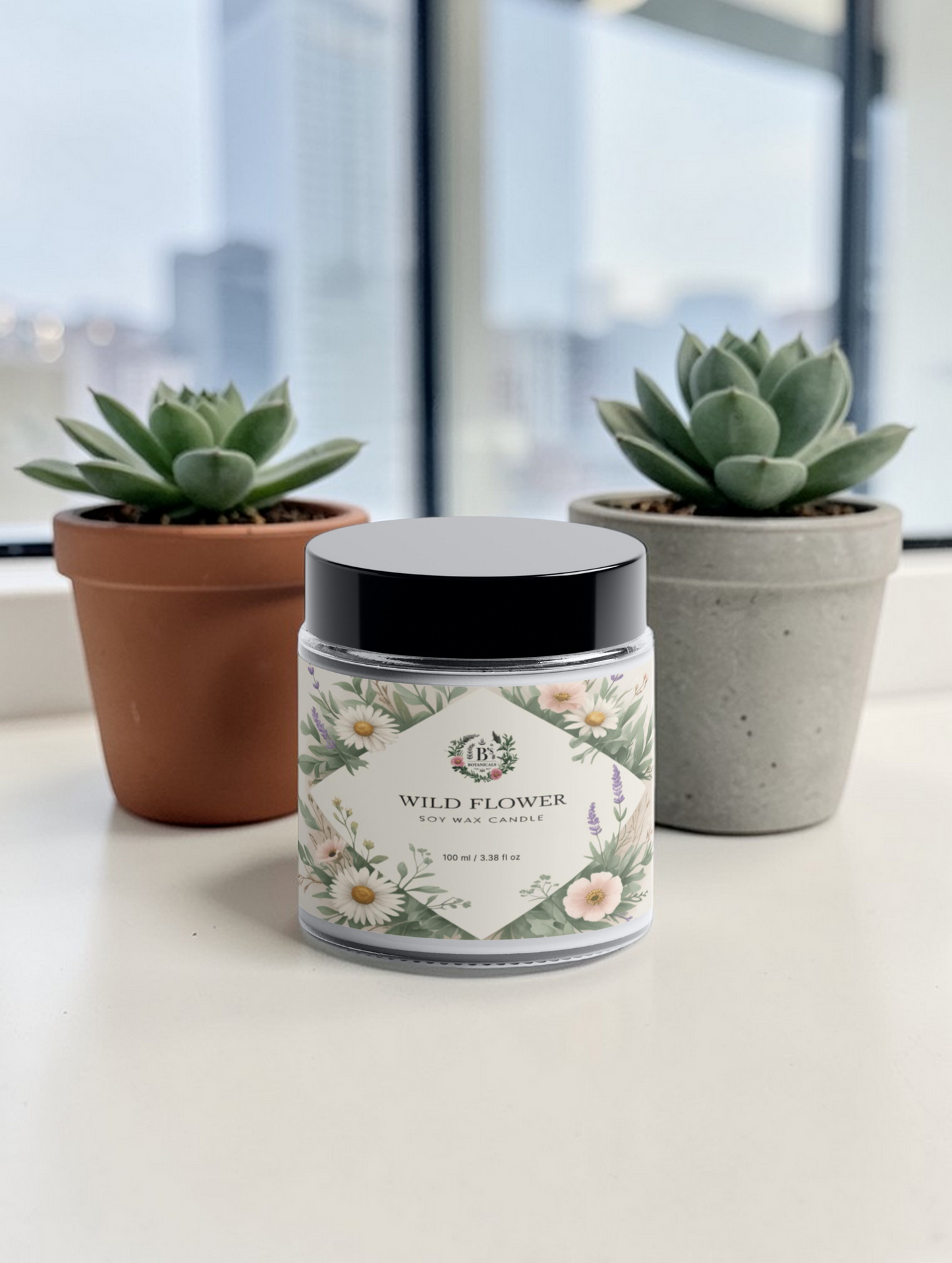 Candle jar labeled 'Wild Flower' with two succulent plants in the background.