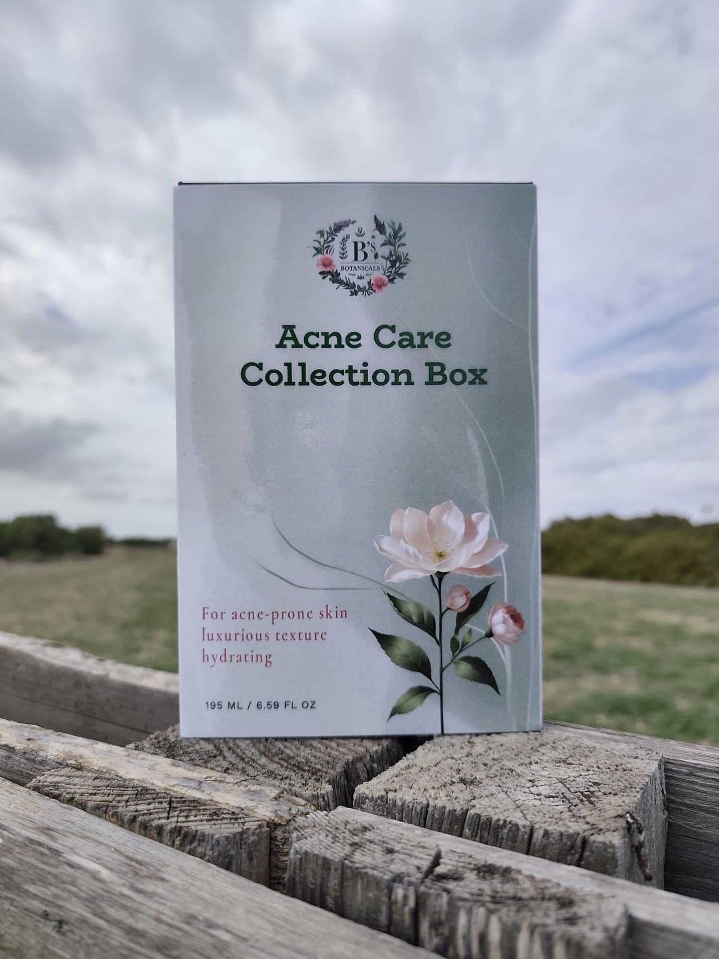 Acne Care Collection Box with floral design on a wooden surface with a field and sky background